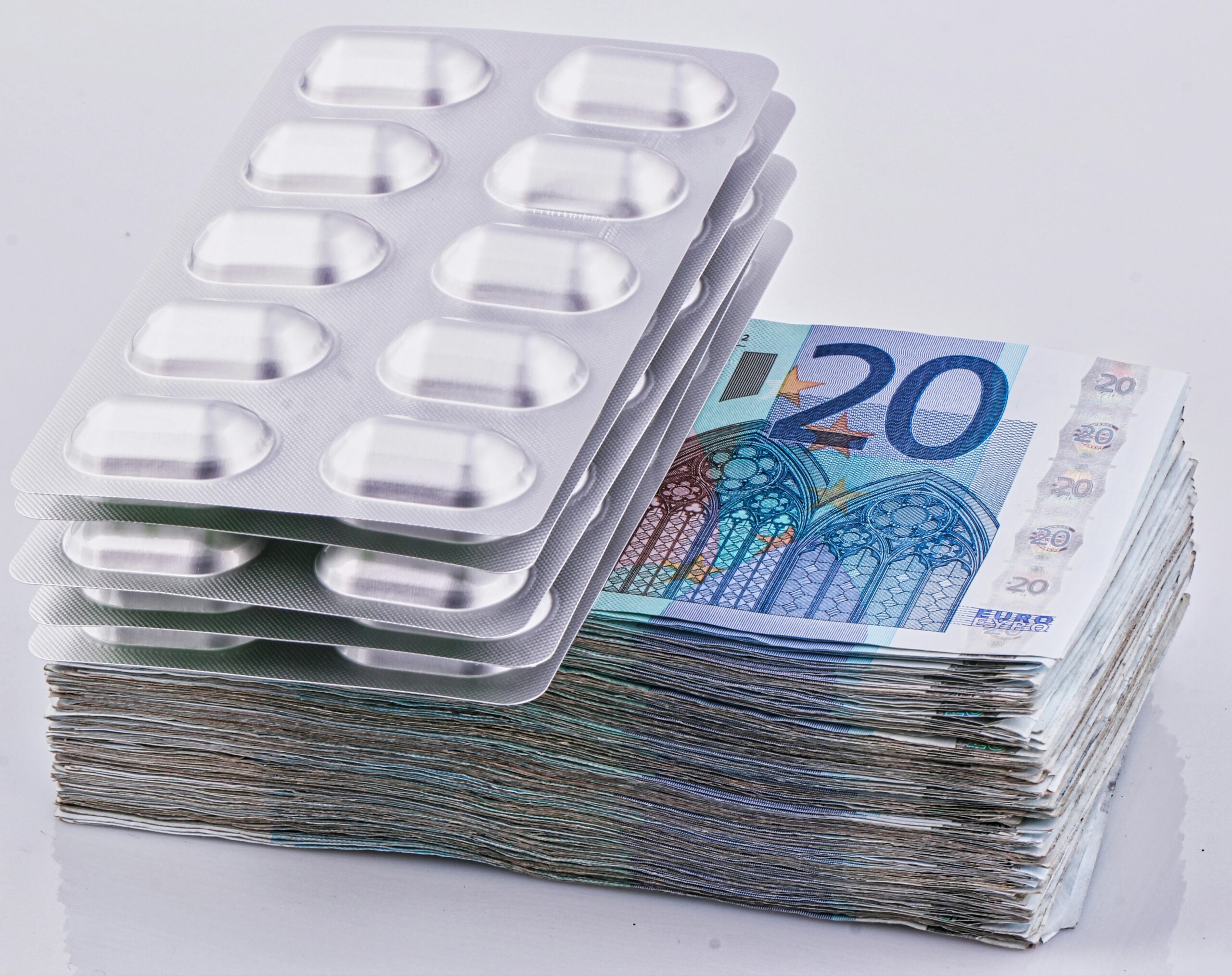 a stack of 20 euro bills next to a pack of 20 pills